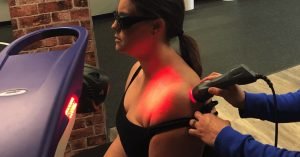 Physical therapist JJ Thomas using laser therapy to improve shoulder healing on patient