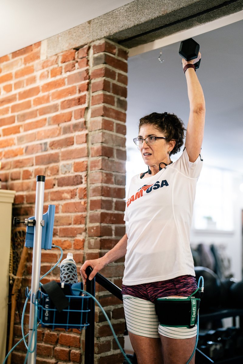 blood-flow-restriction-training female blood flow restriction therapy patient with restriction cuff around thigh lifting weight above head