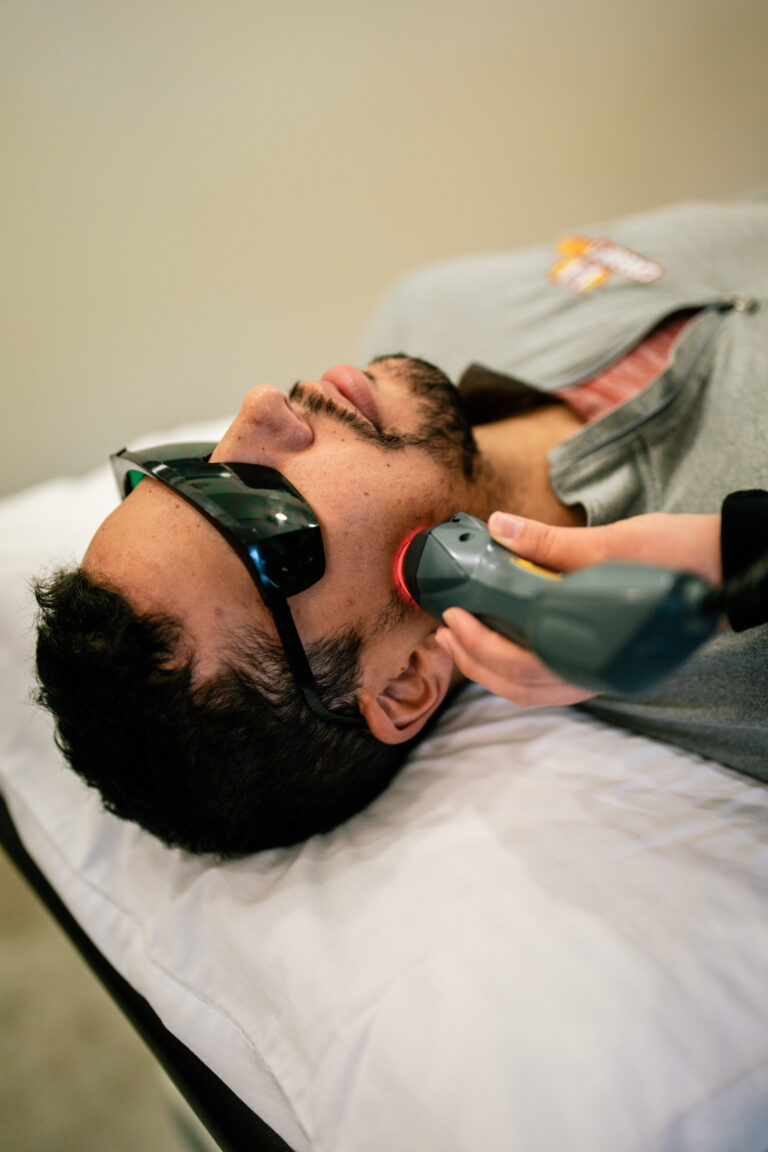 Physical therapist applying laser therapy to a patient to accelerate natural tissue healing.