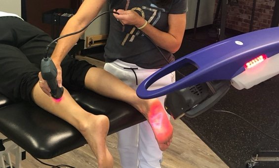 patient on table getting laser therapy on back of calf muscle