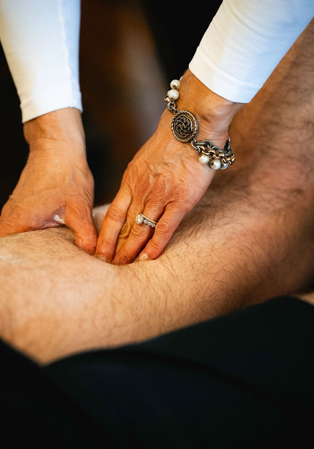 Close-up of a physical therapist performing deep tissue or manual therapy on a patient’s upper leg during a treatment session.