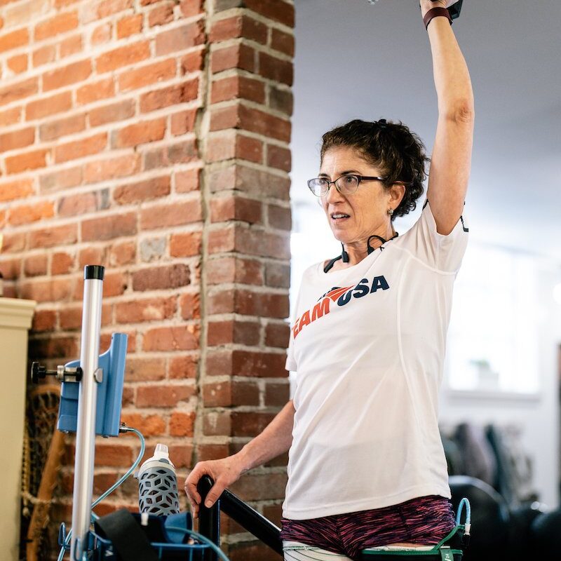 blood-flow-restriction-training female blood flow restriction therapy patient with restriction cuff around thigh lifting weight above head