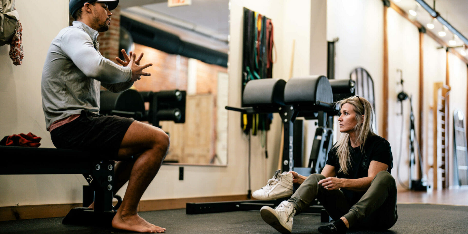 Man with a cap sitting on a bench while talking to a woman therapist on how long the physical therapy session