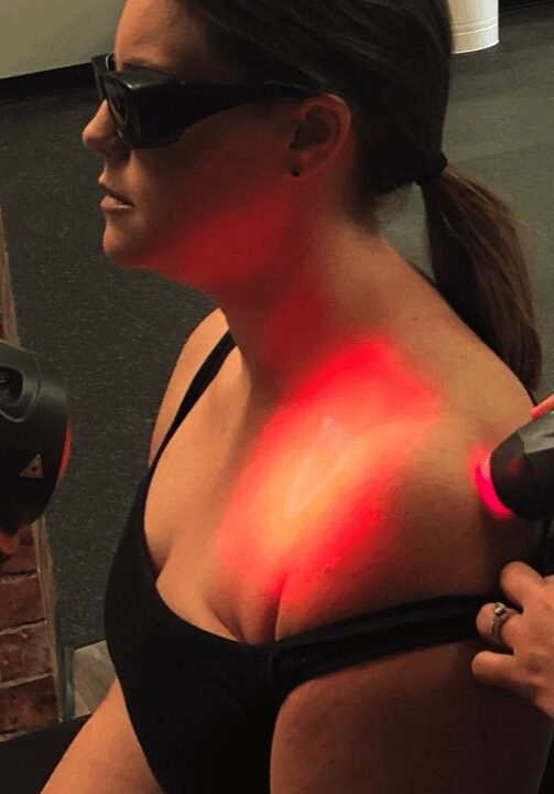Physical therapist JJ Thomas using laser therapy to improve shoulder healing on patient