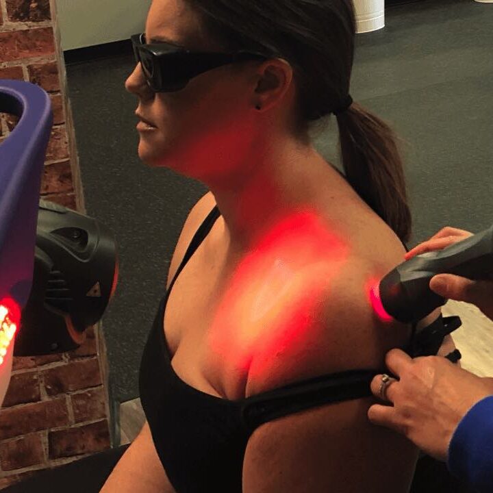 Physical therapist JJ Thomas using laser therapy to improve shoulder healing on patient