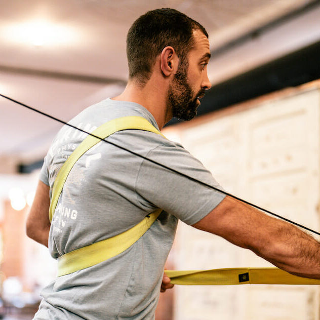 athlete patient at physical therapy in gray t-shirt working on machine to recover from most common shoulder injuries in sports