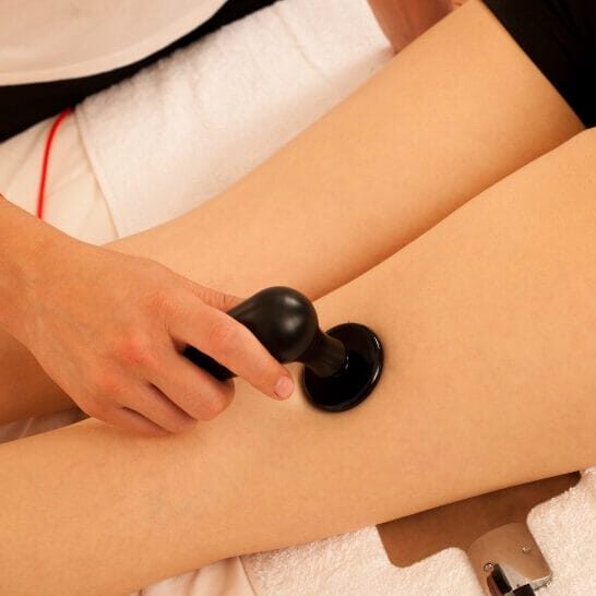 Close-up of a clinician performing TECAR therapy on a patient’s thigh using a handheld radiofrequency device for muscle recovery and pain relief.