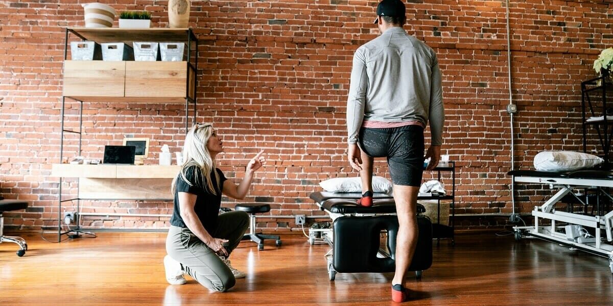 a woman therapist teaching a right physical therapy posture exercises to a man with cap